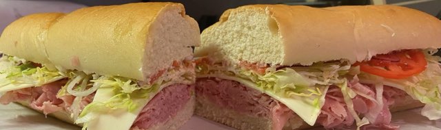 A 12-inch Italian cold sub cut in half showing the layers of meat, cheese and lettuce